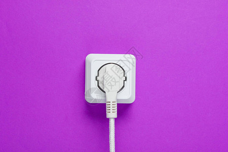 白色电缆插在紫色墙壁背景图片