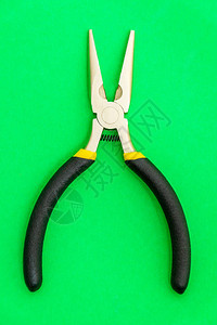 绿色背景电工大师使用带黑色橡胶手柄的单钳子工具图片