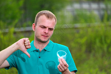 身穿Marrs绿色T恤的义工在压碎的可塑料杯上展示了图片