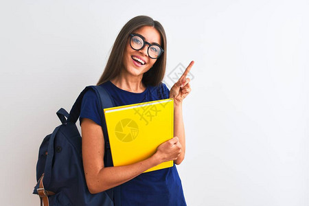 身戴背包眼镜的年轻女学生在孤立的白色背景上持有书籍图片