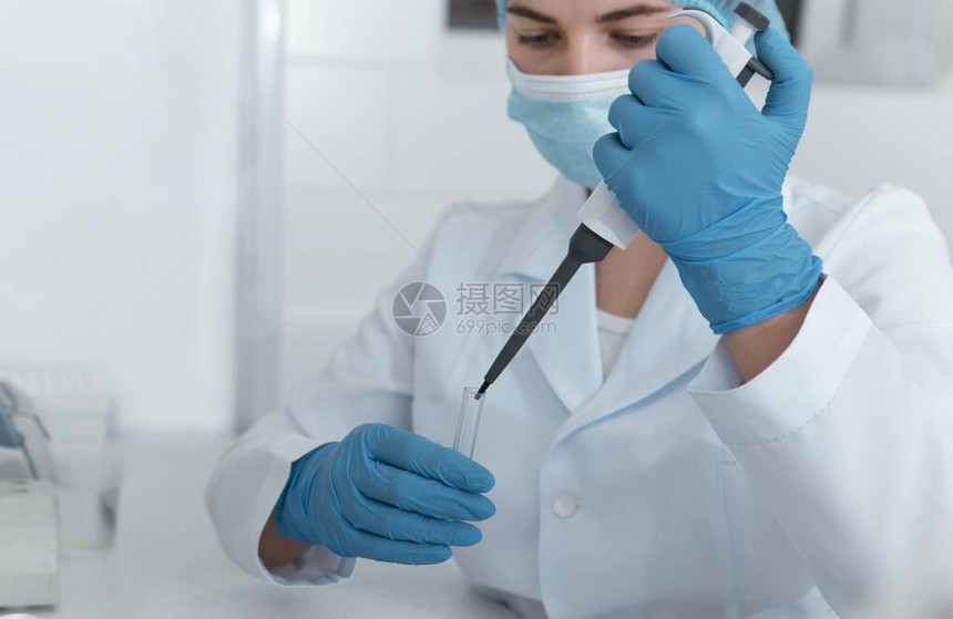 年轻女科学家用大注射器滴入医学实验室试管图片