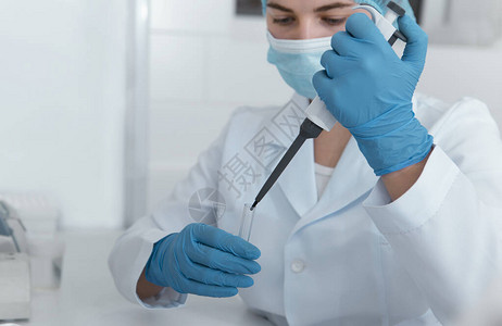 年轻女科学家用大注射器滴入医学实验室试管图片