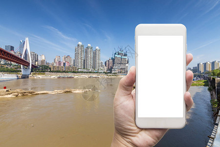 商人手拿着城市背景的白屏智能手机图片