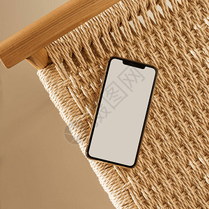 米色背景上的空白屏幕智能手机和柳条长凳平躺顶视图空复制图片