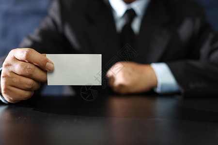 商人在会议室里坐着展示或给予空白商业名片时图片