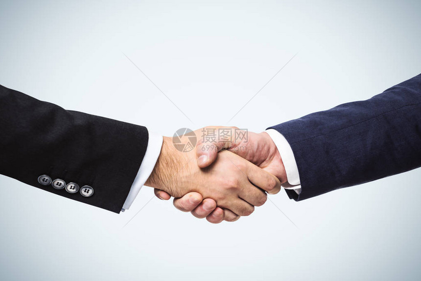 两个商人手握着白墙背景交易概念图片