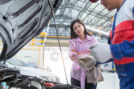 亚洲汽车修理工和顾客女人在汽车服务中心与汽车修理工交谈图片