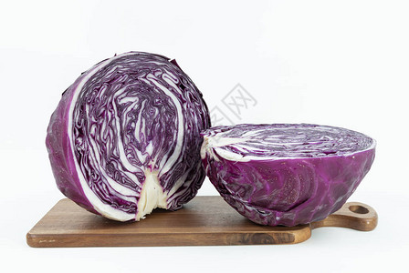 木制切割板上新收获的紫色卷心菜的两半白图片