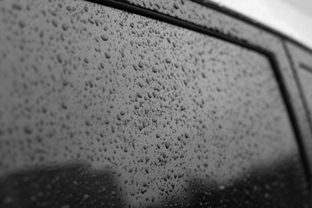 带框架的湿车玻璃黑色玻璃表面与雨滴玻璃上雨滴的自然质感图片