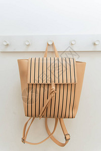 米色背包挂在壁橱的衣架上一个背包挂在商店试衣间的挂钩上背图片