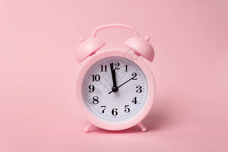 粉红色背景上的柔和粉红色闹钟时间概念最小的组成桌子上的闹钟与粉红图片
