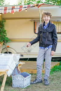站在隐藏的拖车野营车旁参加野餐的少年图片