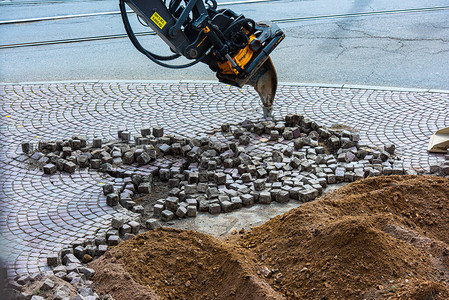 挖掘机使用裂土齿清除街道上的鹅卵石图片
