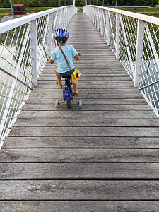 在桥上骑自行车的男孩戴头盔的男孩德拉瓦河上图片