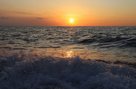 海日落橙色天空地平线上的太阳在落日的光芒中溅起的海浪图片