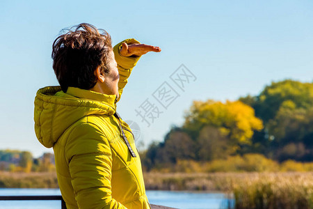 穿黄色夹克的女人在旅行时看远处图片