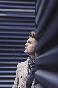 肖像英俊的时尚男模特穿着优雅的外套在蓝墙附近摆姿势图片