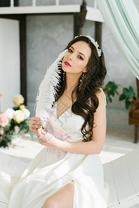 漂亮的年轻女孩新娘的闺房早晨有豪华头发和化妆的新娘手工发饰拿着白背景图片