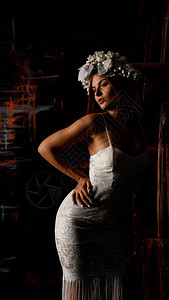 穿着白裙子和花圈的漂亮感美女在黑暗工作图片