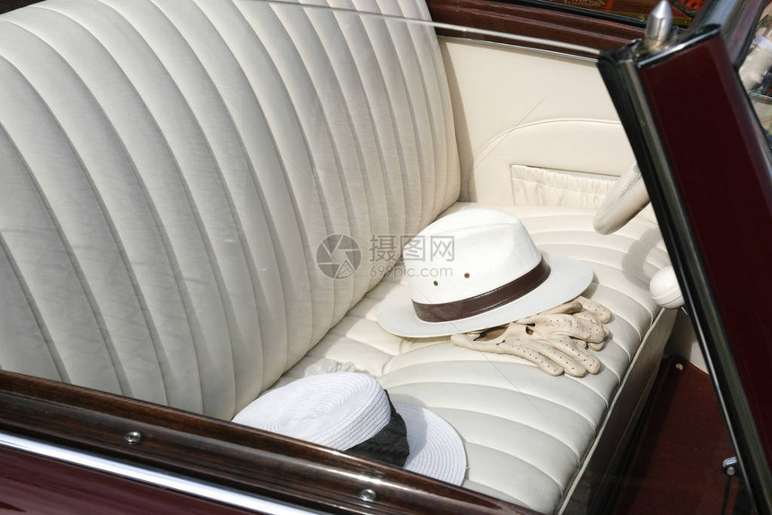 白色经典旧式的帽子和手套在皮革车座椅上修饰图片