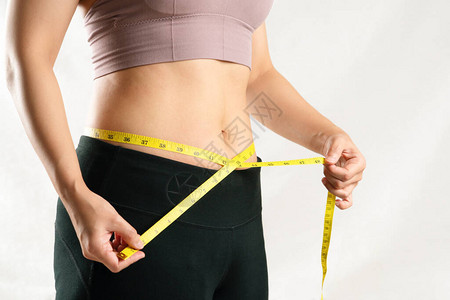 年轻妇女用计量胶带妇女饮食生活方式概念测量其肚图片