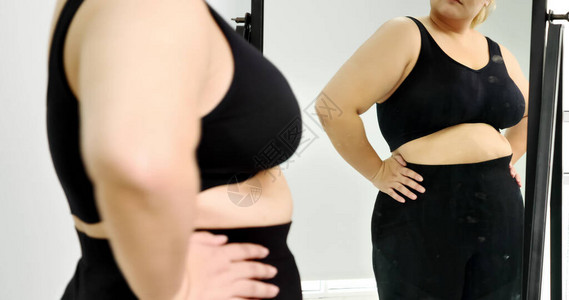 胖子女人站在镜子里看着她的肚图片