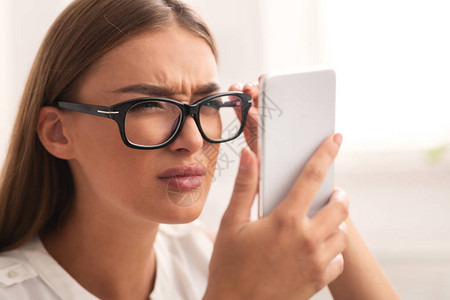 女孩通过有视觉问题的眼镜在手机屏幕上观看图片