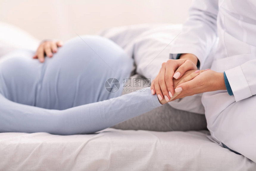 无法辨认的医生持有孕妇手持支病人在室内卧床躺着的图片