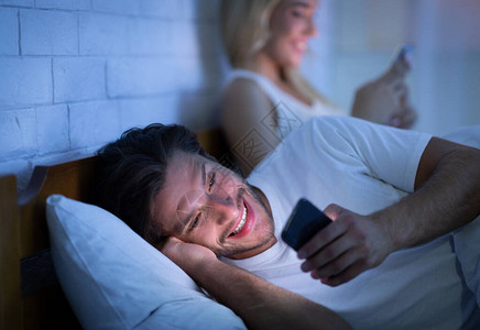 欺骗和不忠丈夫通过手机在卧室里与妻子通电话低光图片