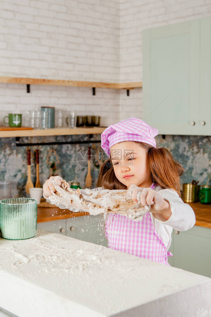 厨房里的女孩揉面团和撒面粉图片