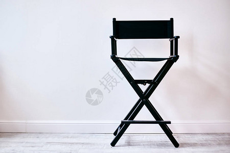靠着白墙的黑色导演椅化妆椅背景图片