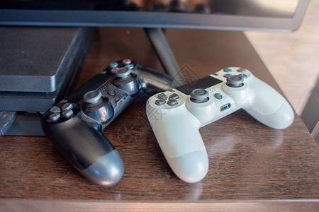游戏机上的一对操纵杆奇瑞和白色放在电视和游戏机背景图片