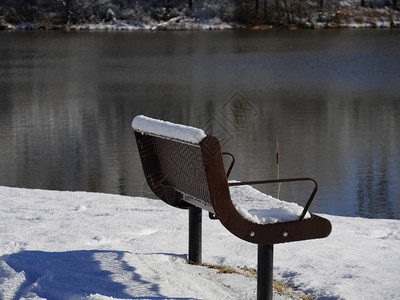 在寒冷的冬季清晨面对池塘的雪覆盖图片