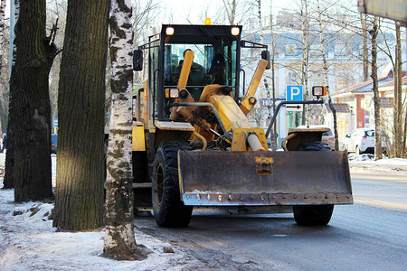 拖拉机在肮脏的雪城清理道路图片