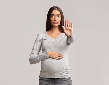 怀孕资料怀孕女孩停止在灰色工作室背景上站立图片