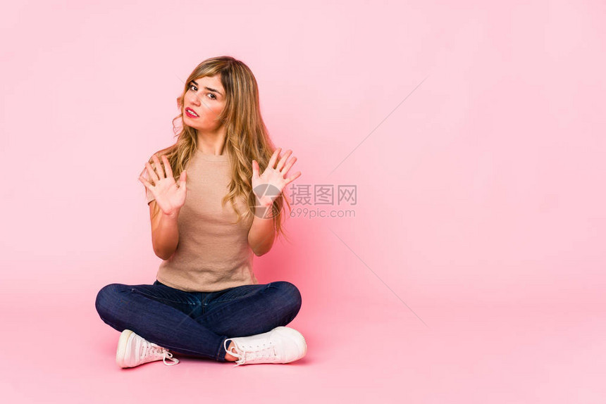 坐在粉红色工作室的金发美女拒绝有人表现出厌恶的姿态笑声这图片
