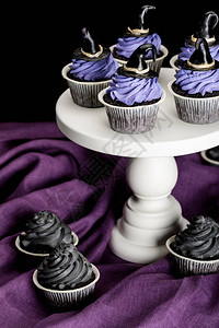 美味的万圣节纸杯蛋糕白色站在紫色布衣上图片