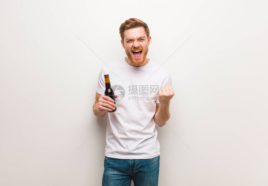 年轻的红发男人拿着啤酒图片