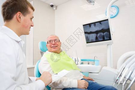 在牙科诊所坐在扶椅上看牙医的老年人图片