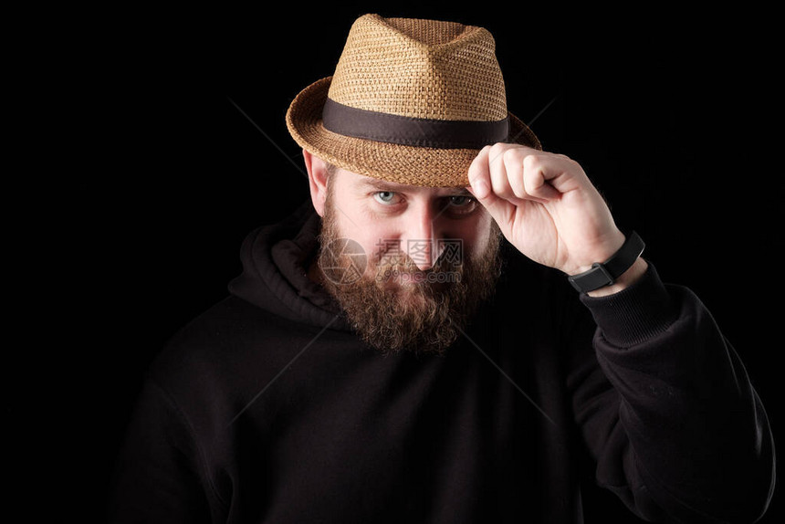 一个留胡子的白人男子在问候时触碰他的帽子身着黑衣服背图片