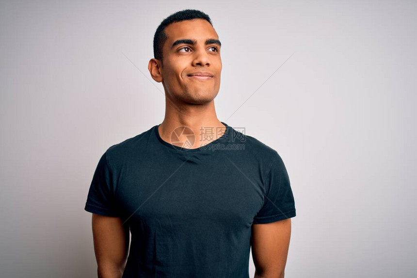年轻英俊的非裔美国人穿着短袖T恤站在白色背景上微笑地仰望着侧面图片