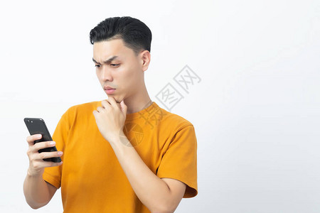 年轻英俊的亚洲男子在阅读智能手机留言后思考图片