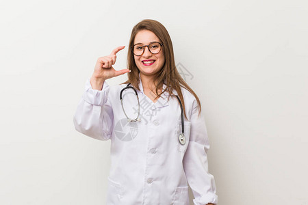 年轻女医生站在一堵白色的墙上握着一些小东西与食腐者图片