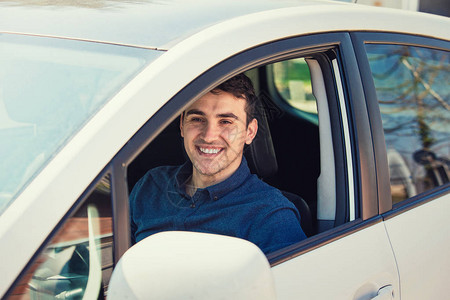 正面微笑的年轻男子司机坐在方向盘后面图片