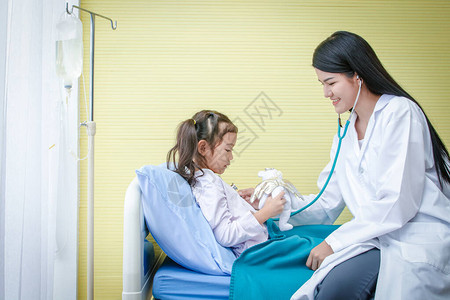 亚洲女医生用听诊器检查病床上的一个小女孩的心跳儿图片