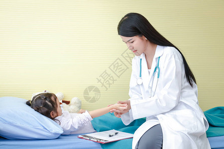 医生用一只手在病床上的一个小女孩的右手腕上按住脉搏图片