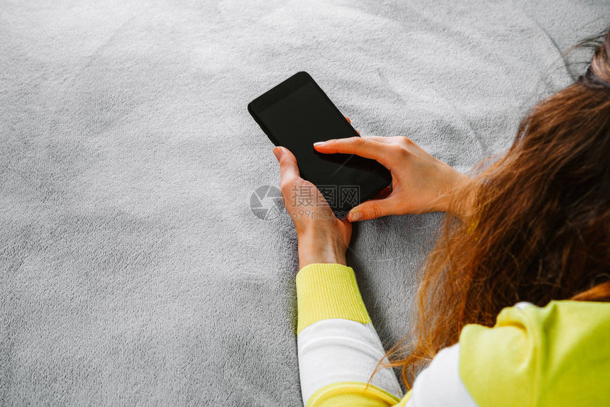 女人躺在床上手拿着智能手机图片