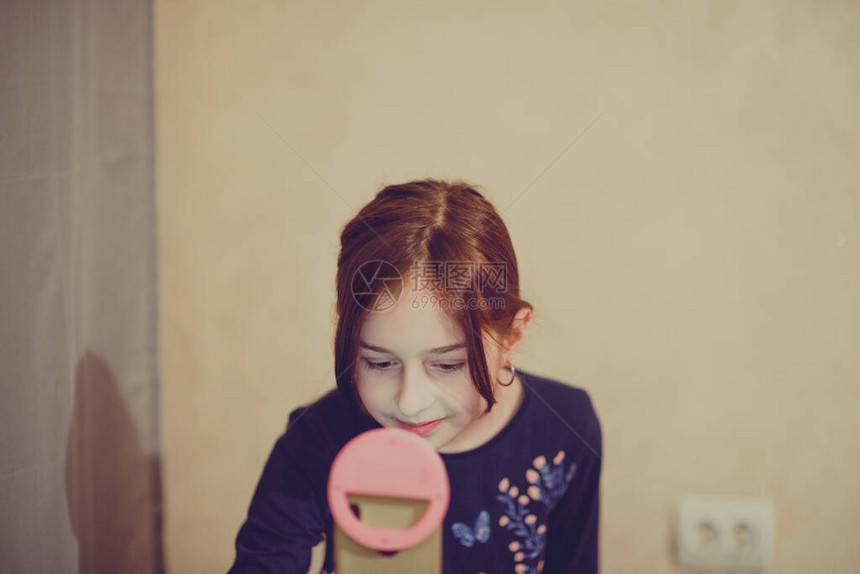 快乐的年轻女子在白色背景上自拍女孩用独脚架或自拍杆摄自己的视频博主视频博客这个女孩为Internet或网络制图片