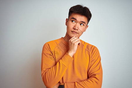 年轻的亚洲华人穿着橙色毛衣站在孤立的白色背景上图片