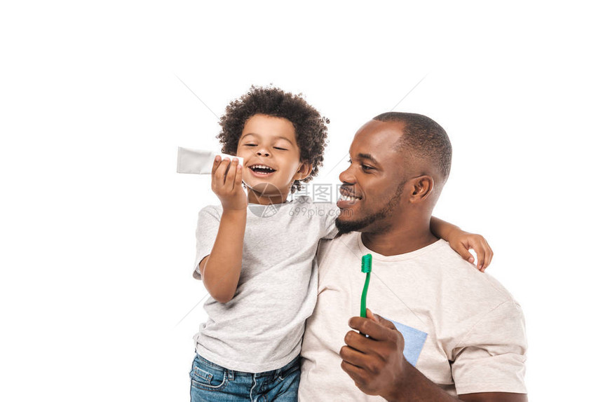 快乐的非洲裔美国男孩在快乐的父亲身边看着牙膏图片